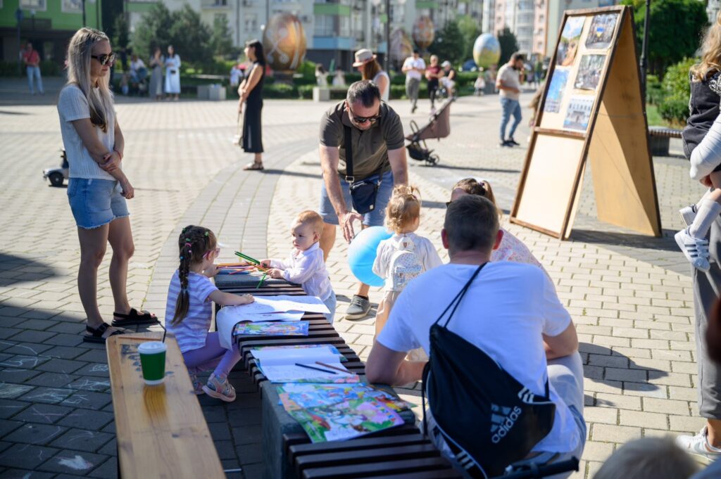 Діти малюють кольоровими олівцями на вулиці.