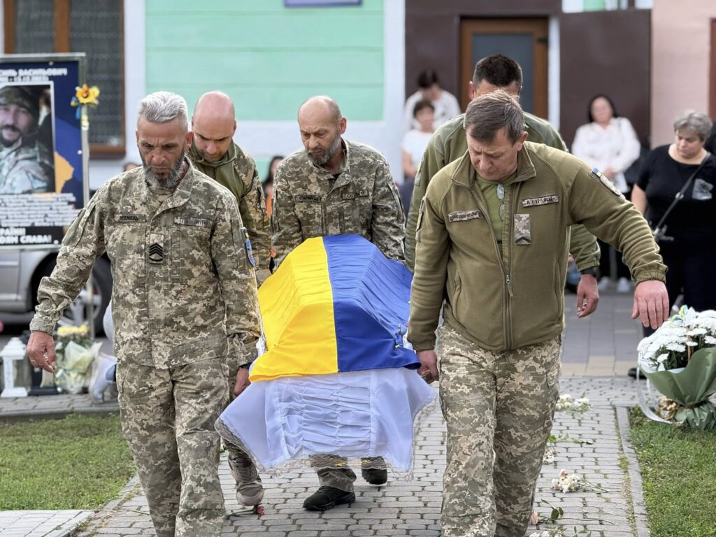 Військові несуть труну з прапором України.