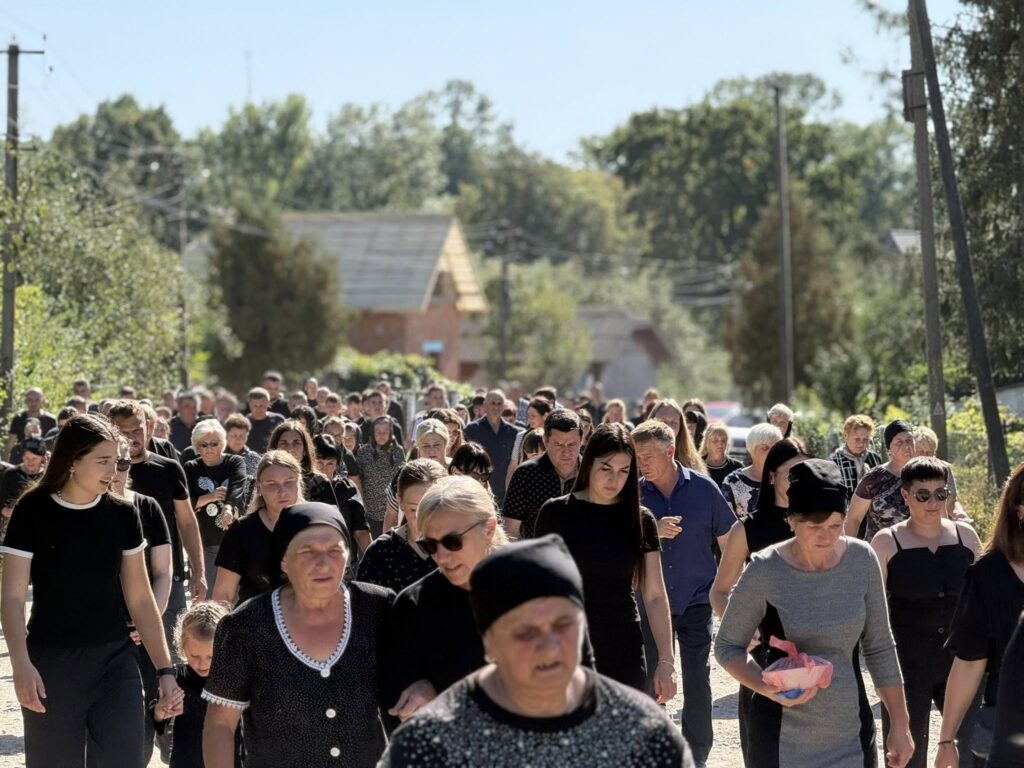 Група людей іде вулицею, яскравий сонячний день.