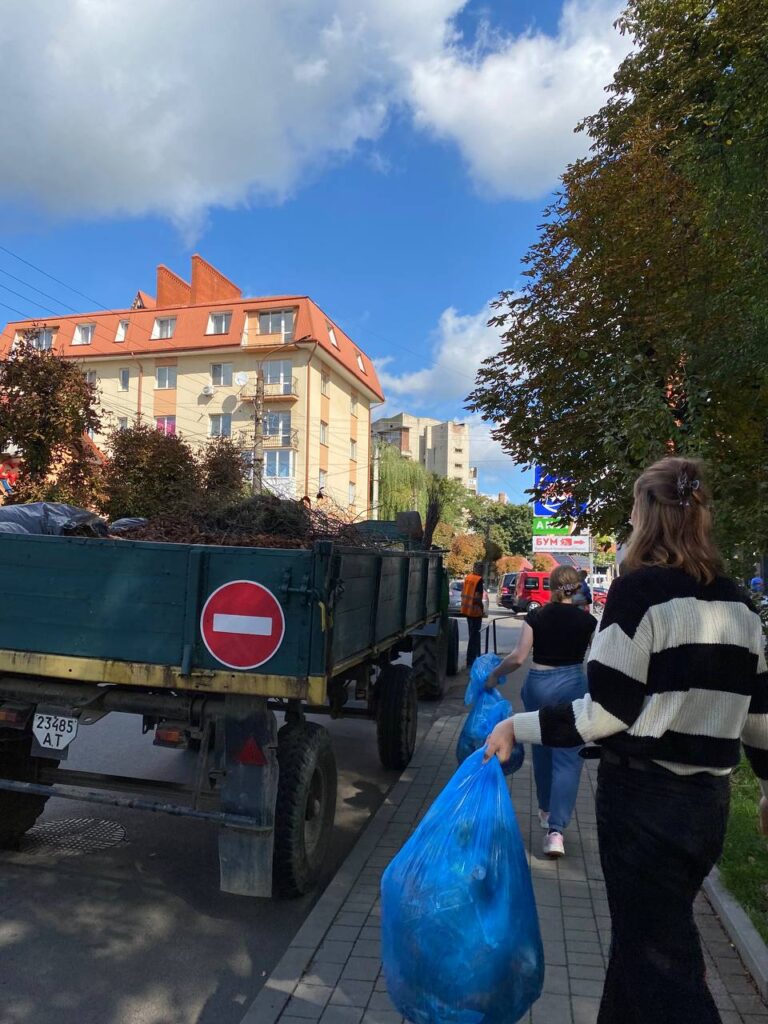 Люди несуть пакети сміття по вулиці.