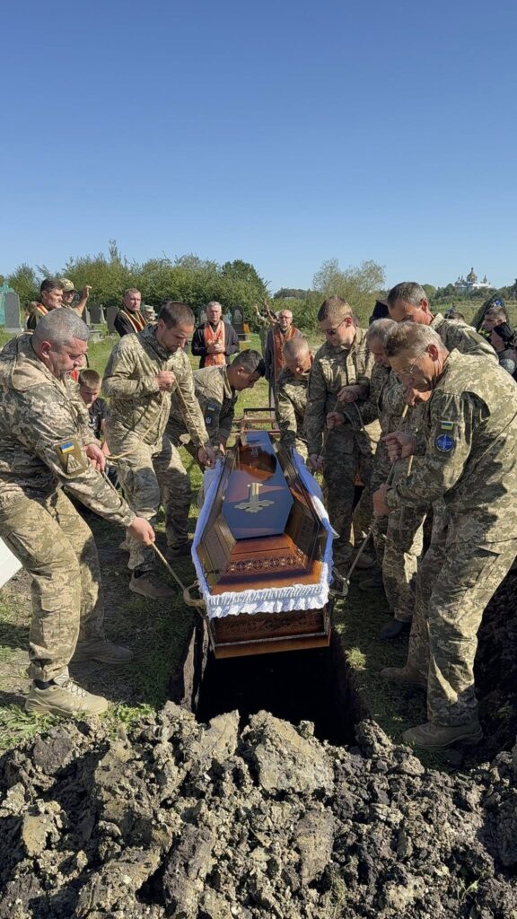 Військові опускають труну в землю на похороні.