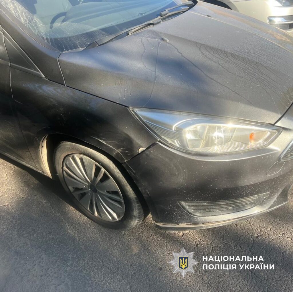 Пошкоджене переднє крило чорного автомобіля на дорозі.