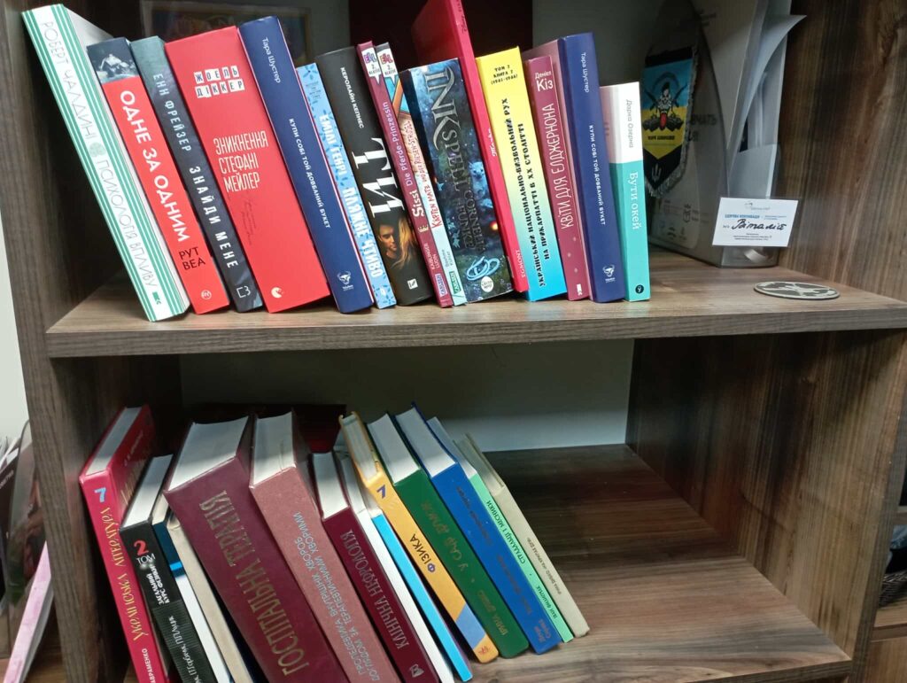 Книжкова полиця з різноманітними книгами.