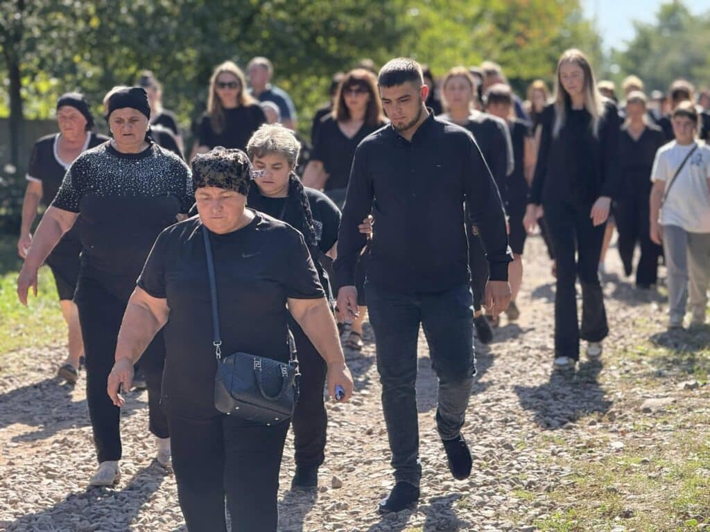 Люди у чорному йдуть по стежці на природі.