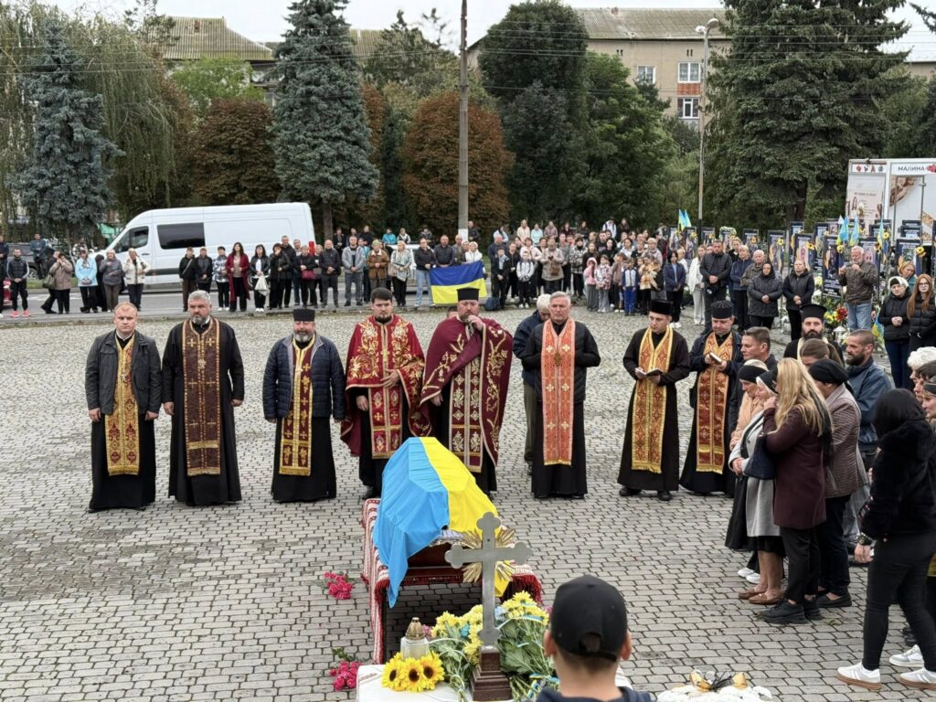 Церемонія прощання з труною, вкритою українським прапором.