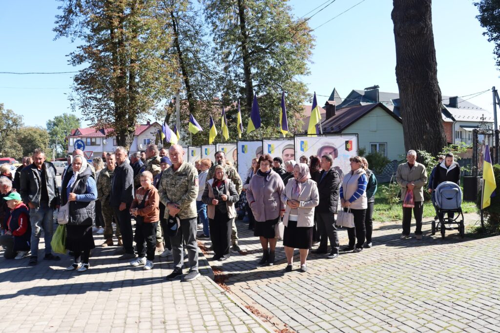 Люди зібралися на вулиці під українськими прапорами.