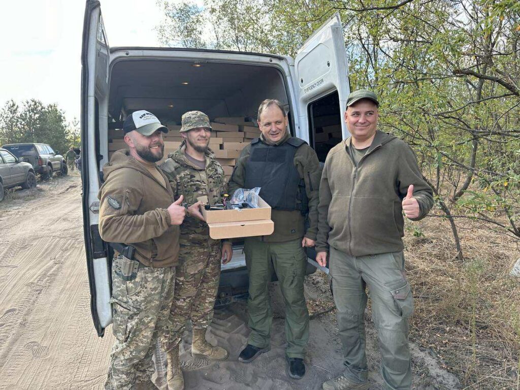 Військові отримують пакунки біля вантажівки в лісі.