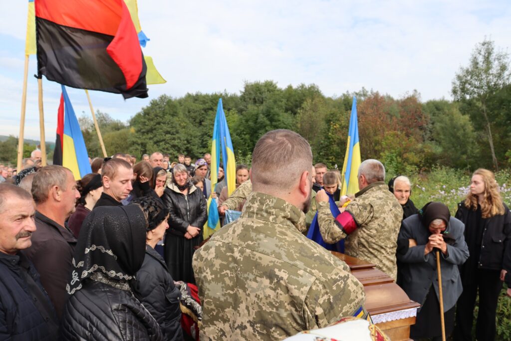 Похоронна церемонія з українськими прапорами на тлі