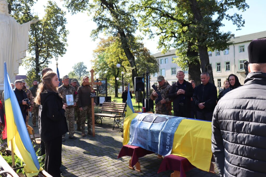 Меморіальний захід з українським прапором та військовими.