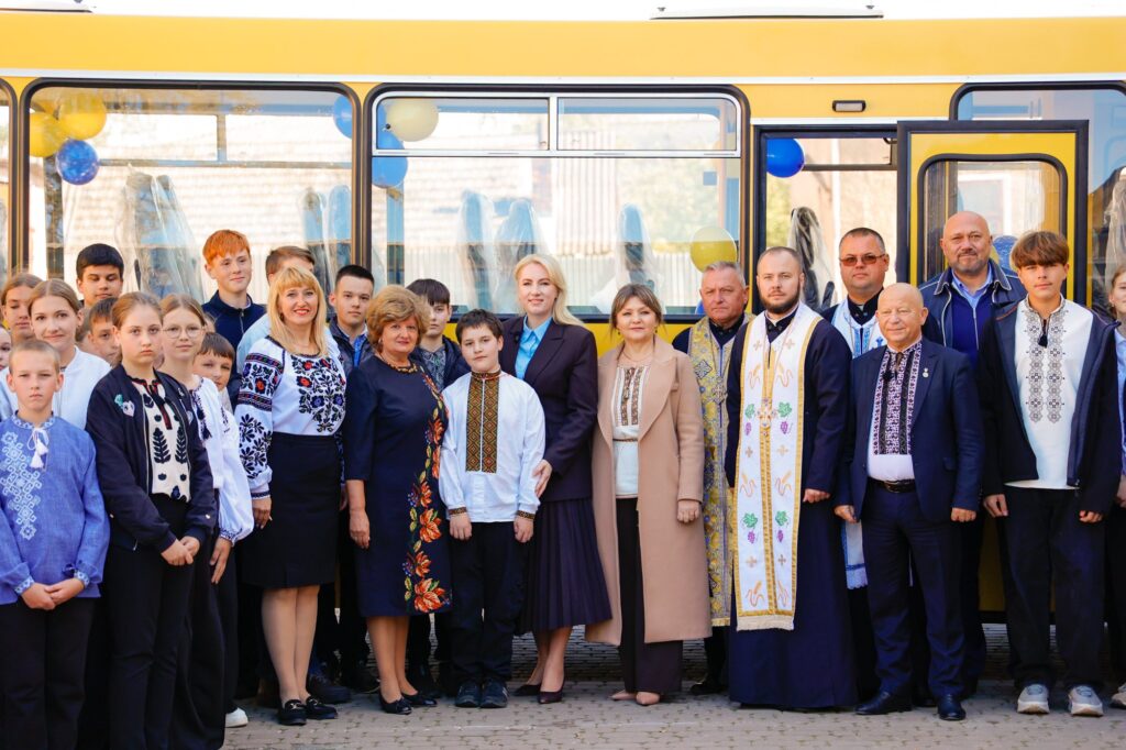 Група людей біля шкільного автобуса на вулиці.