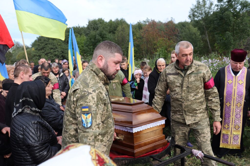 Військові прощаються з побратимом, українські прапори.