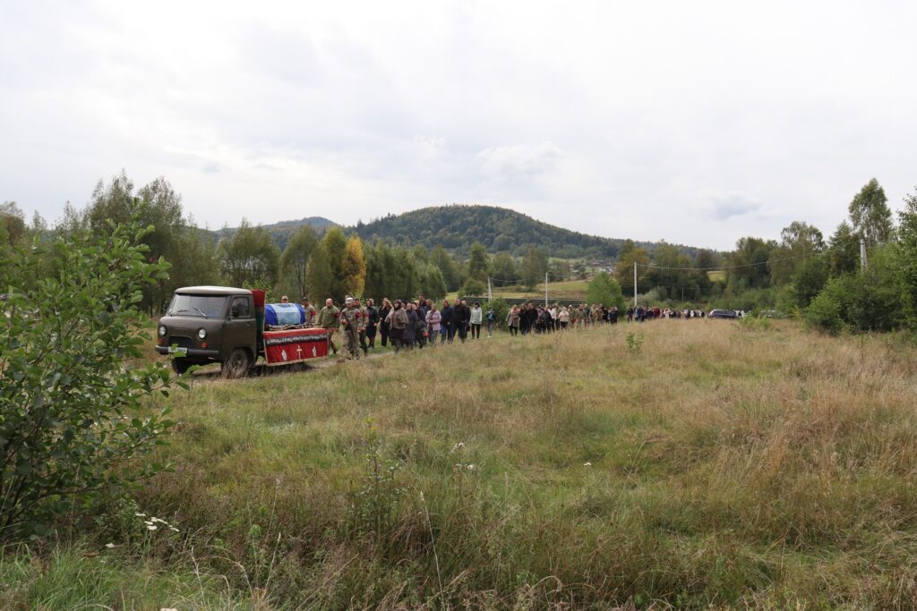 Процесія людей з труною в селі