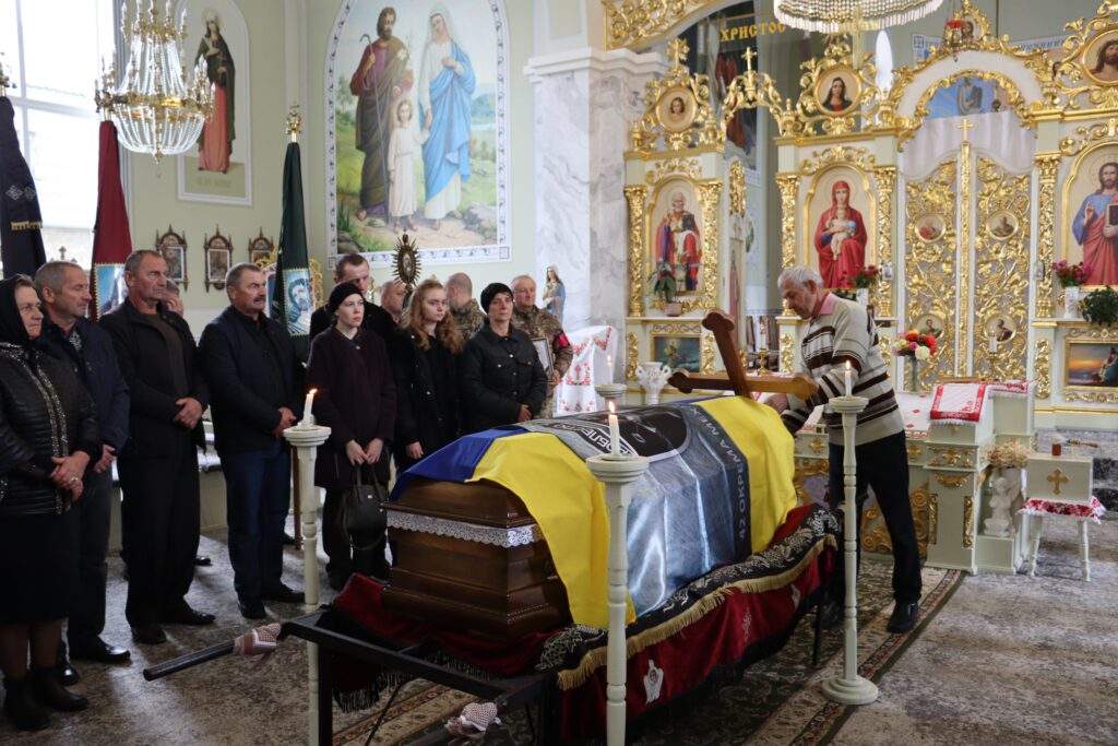 Похоронна церемонія у церкві з труною та людьми.
