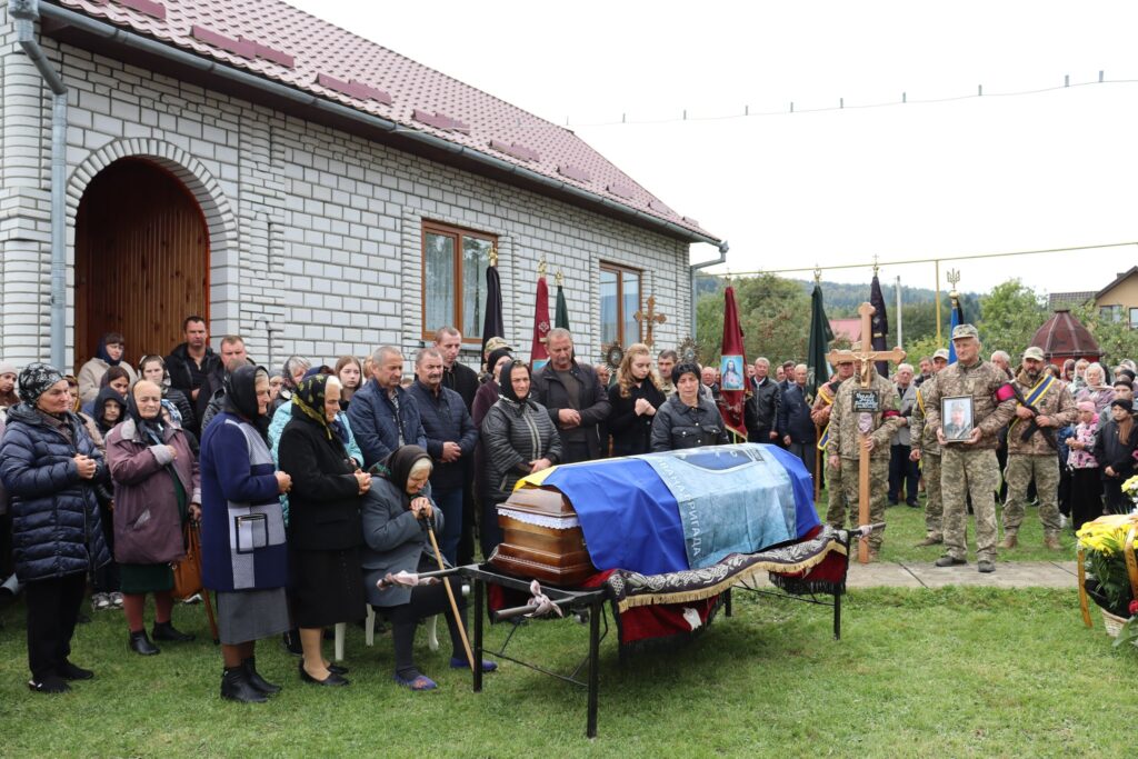 Люди зібралися на похорон біля будівлі.