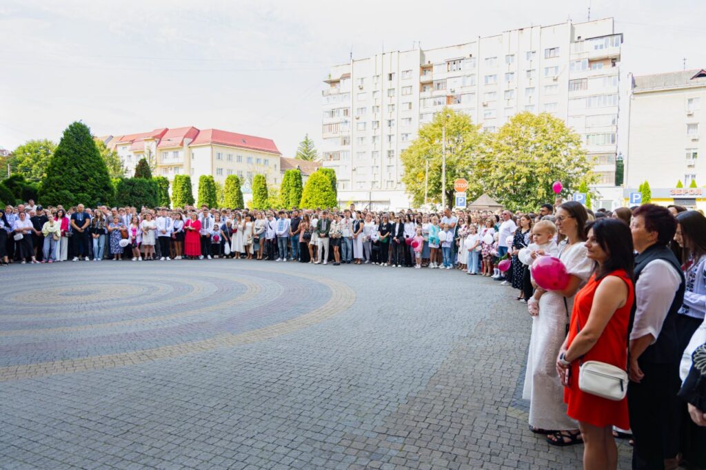 Група людей стоїть на брукованій площі.