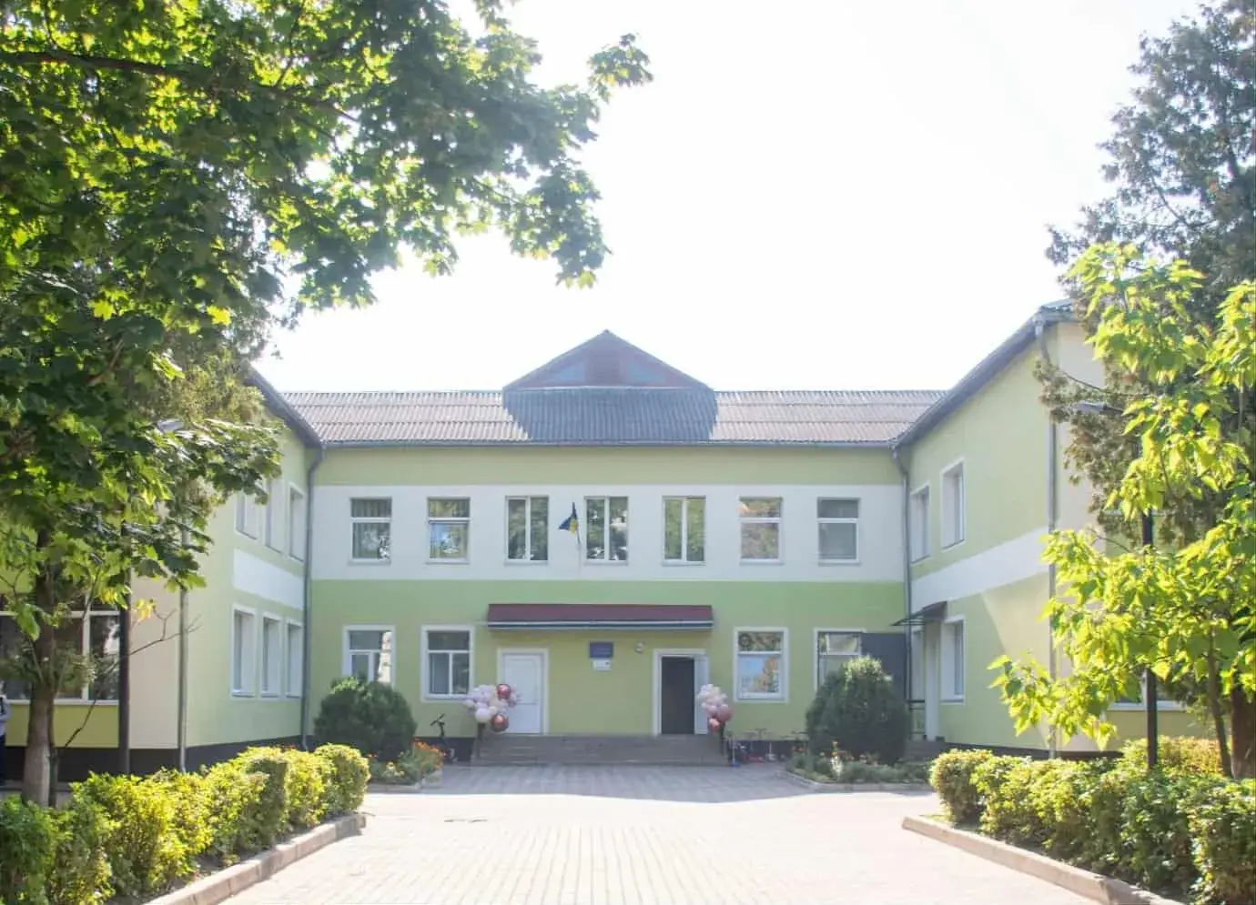 Будівля школи з зеленими деревами навколо.