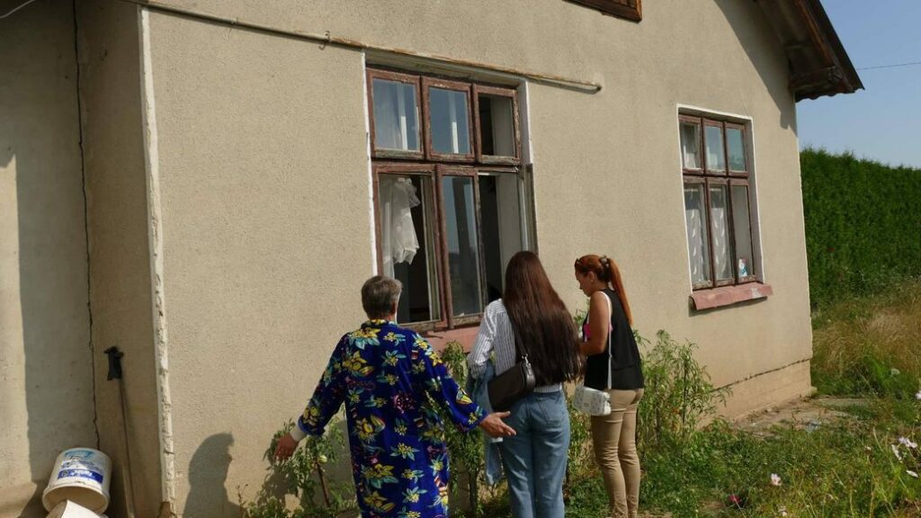 Три жінки біля вікна старого будинку.
