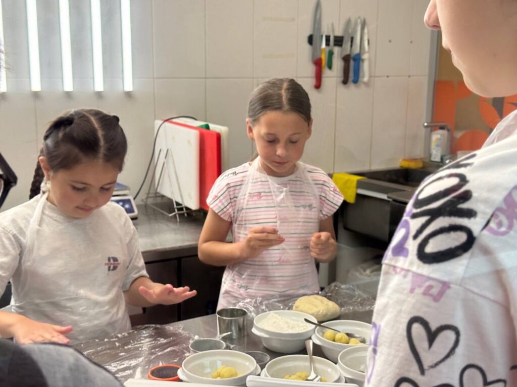 Діти готують на кухні з тістом і борошном.