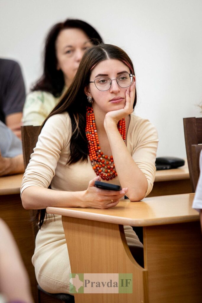 Жінка з телефоном на конференції, сидячи за столом.