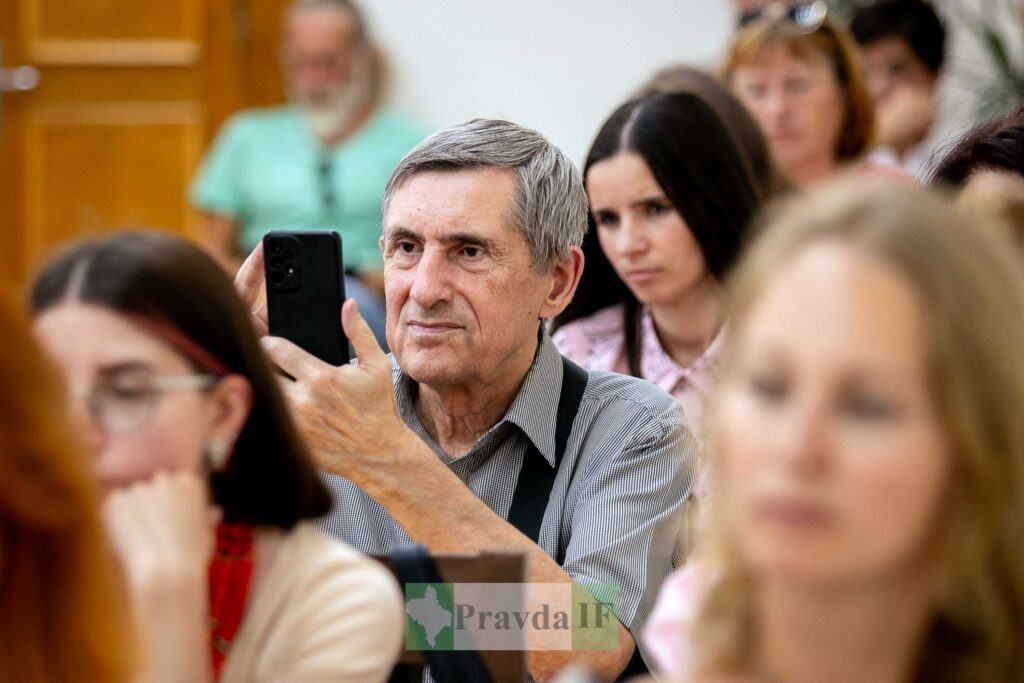 Чоловік фотографує на телефон під час заходу.