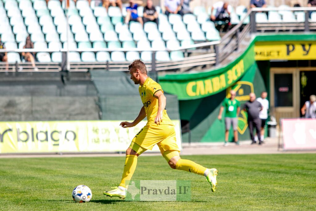 Футболіст у жовтій формі з м'ячем на полі