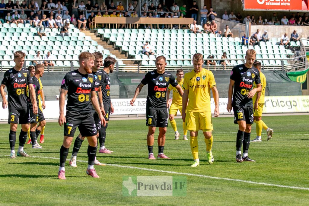 Футбольний матч командами у чорній і жовтій формі.