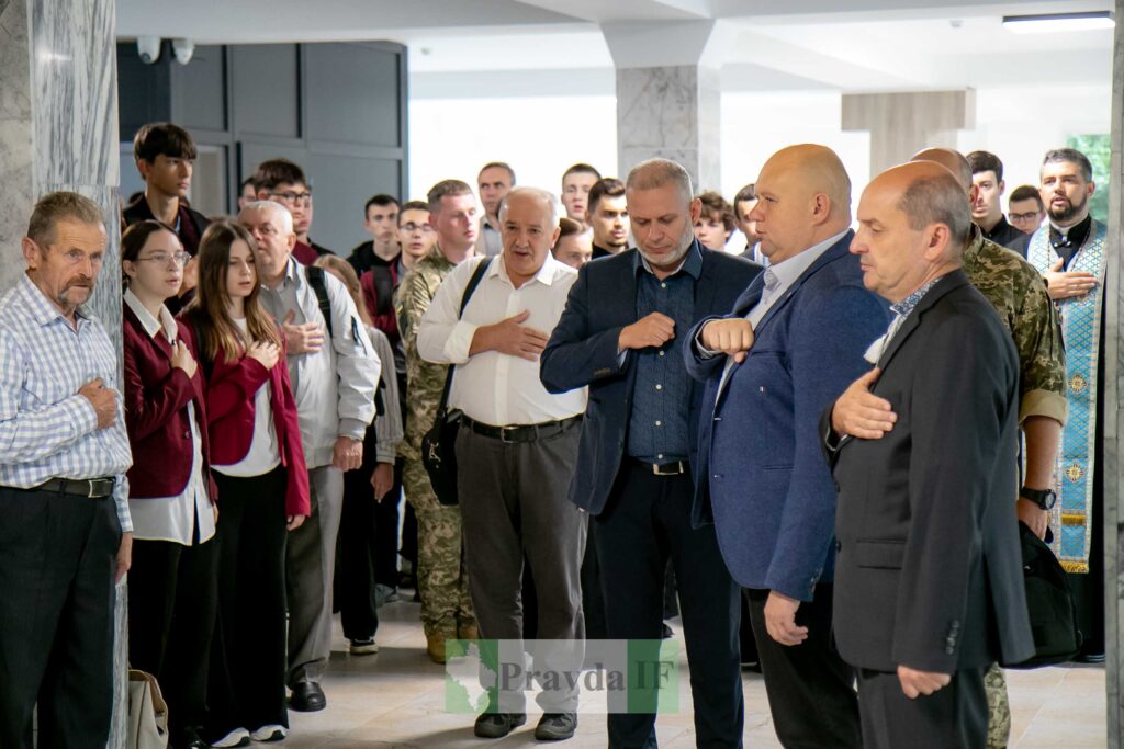 Люди стоять з руками на серцях у будівлі.