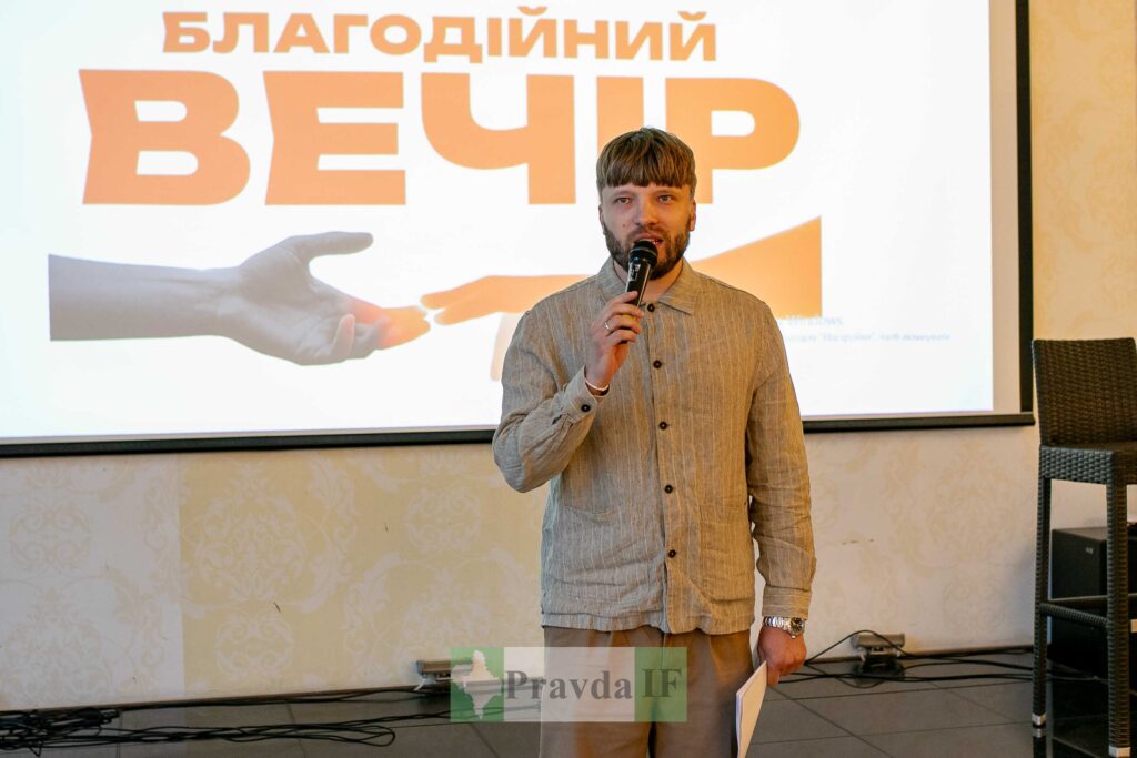 Ведучий благодійного вечора з мікрофоном на сцені.