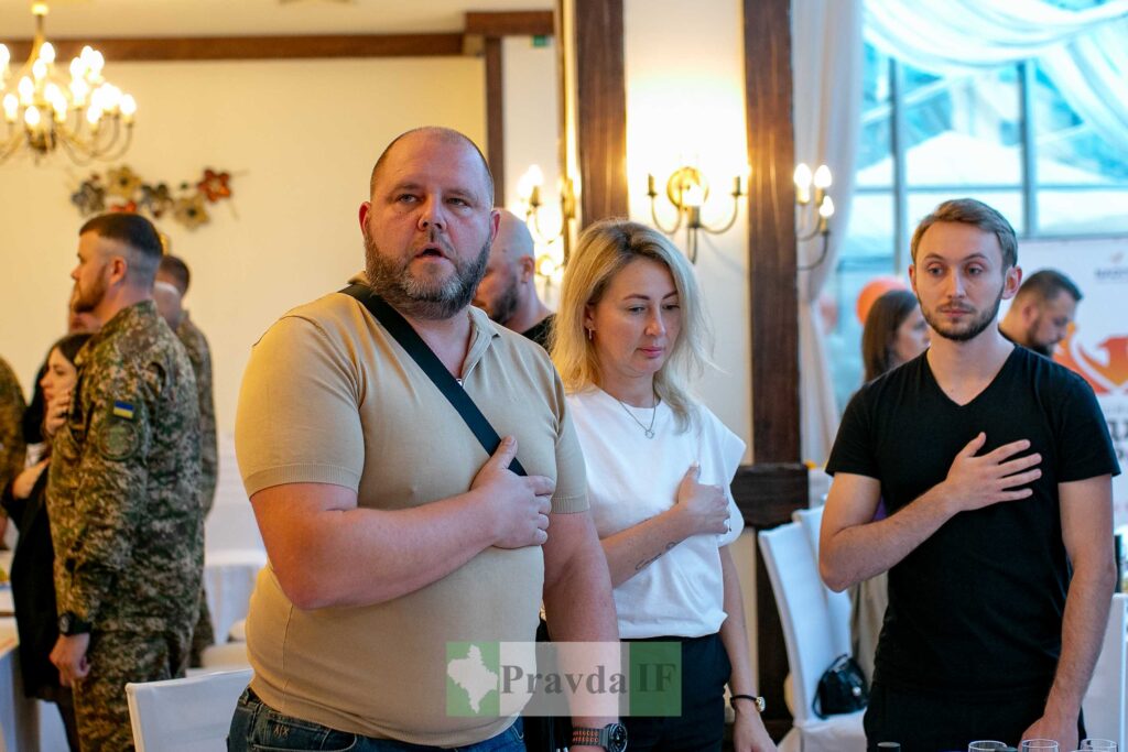 Люди на офіційному заході з національними прапорами.