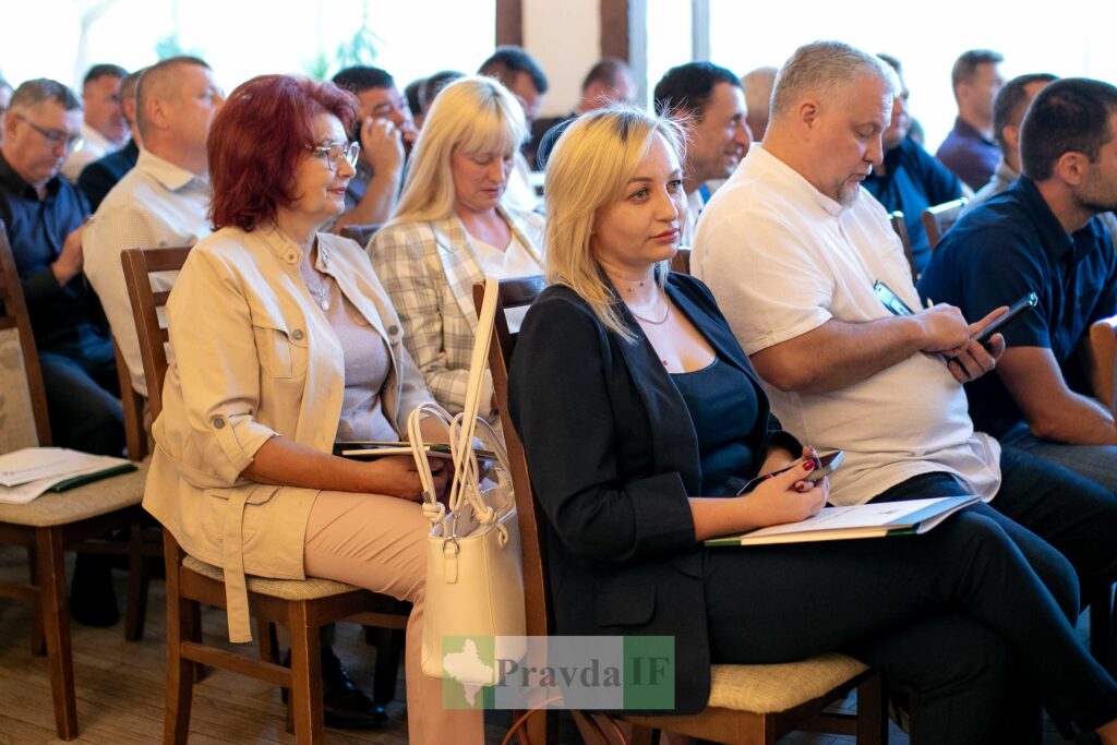 Люди сидять на конференції з блокнотами