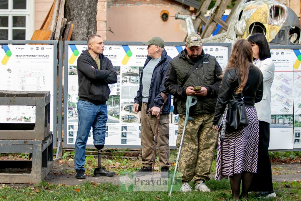 Люди обговорюють проєкти реконструкції на відкритому повітрі.