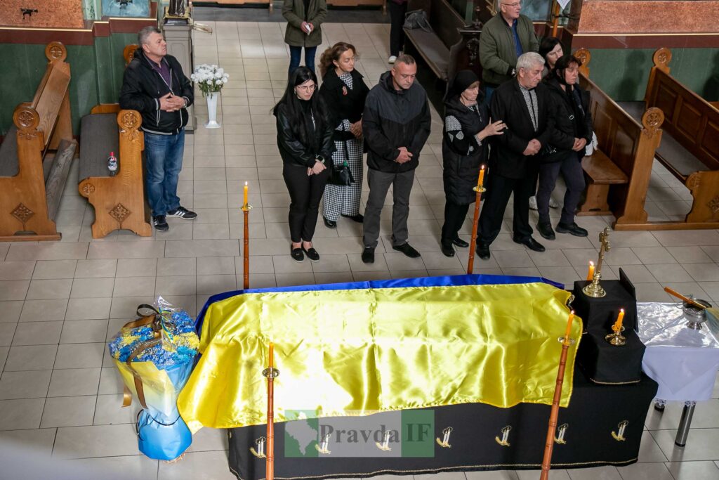 Похоронна процесія з прапором України, людей у церкві