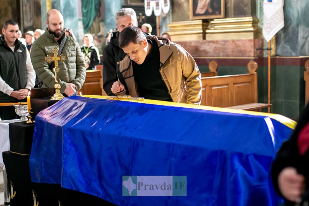 Похоронна церемонія з синьо-жовтим прапором на труні.