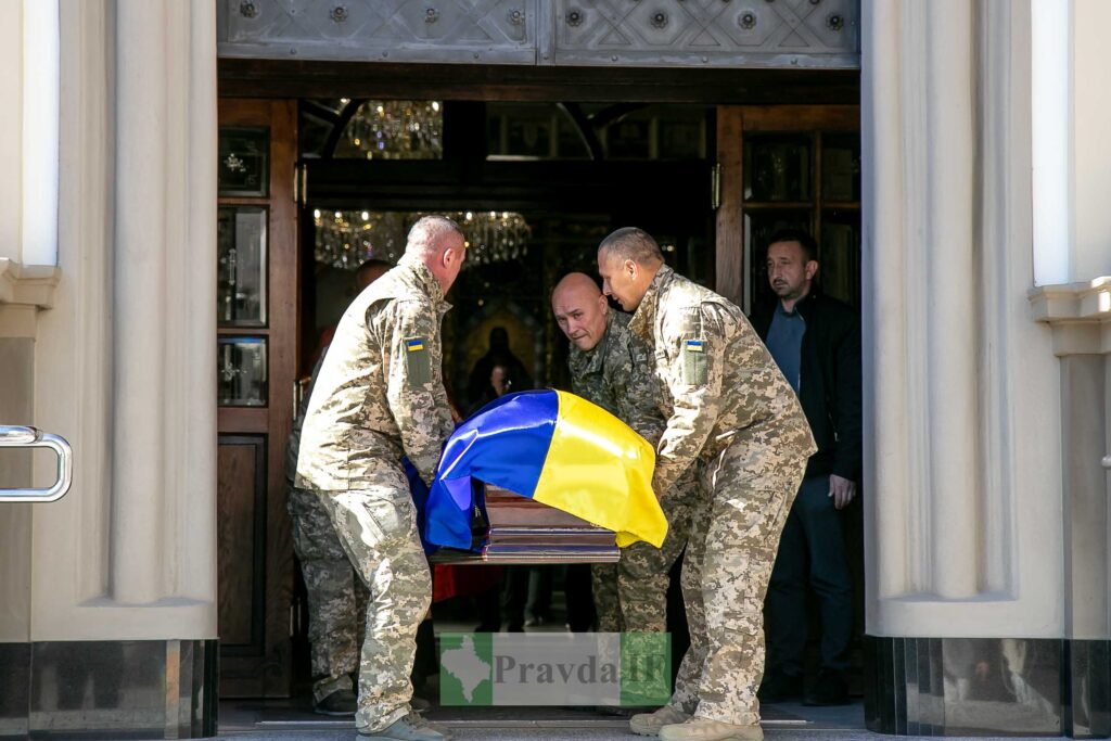 Українські військові несуть труну, накриту прапором.