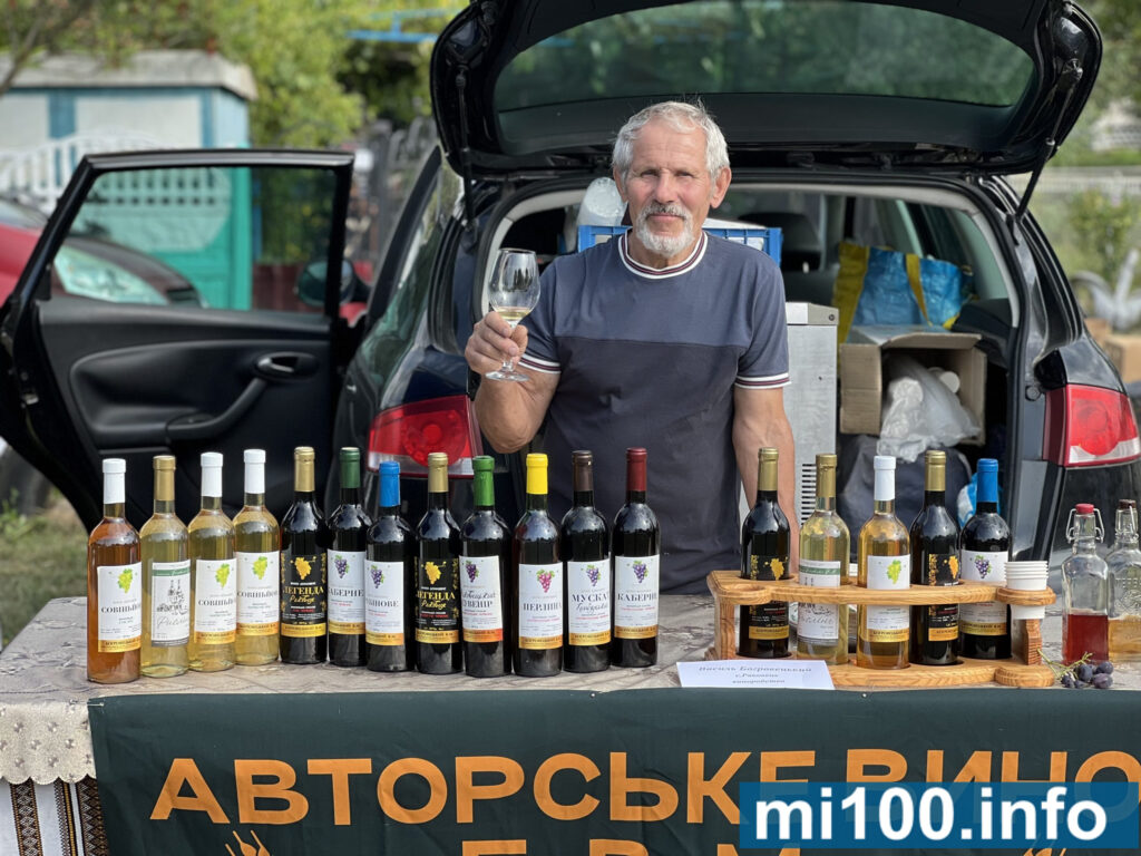 Чоловік продає авторське вино на ярмарку.