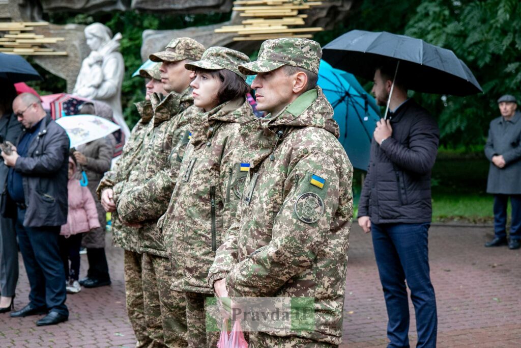 Українські військові на урочистому заході під дощем.