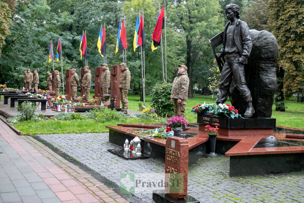 Пам'ятник Небесній сотні з квітами та прапорами.