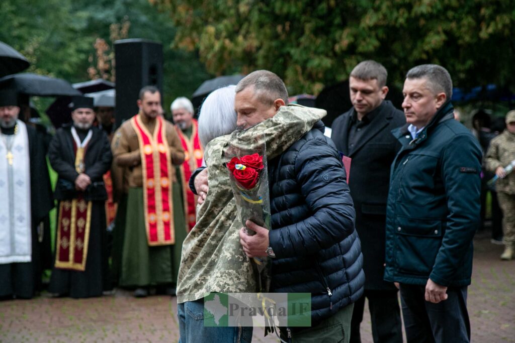 Люди обіймаються під час церемонії на вулиці.