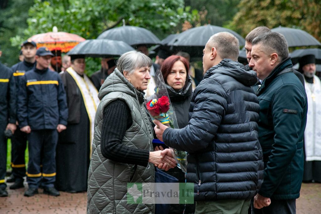 Люди під дощем з парасольками на вулиці.