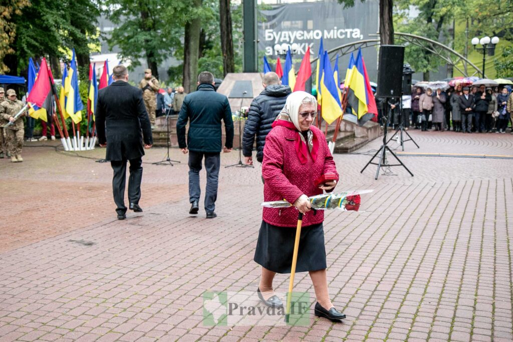 Церемонія пам'яті з українськими прапорами, жінка з квітами.