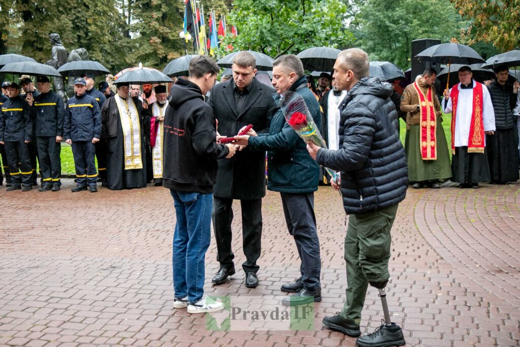 Церемонія вручення нагород на вулиці під дощем.