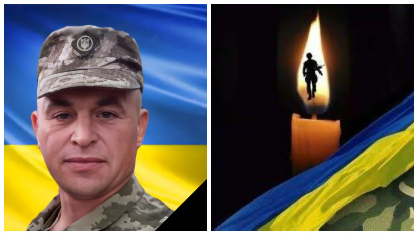 Український військовий на фоні національного прапора.