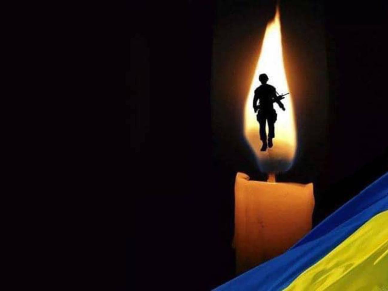Солдат у полум'ї свічки над прапором України.