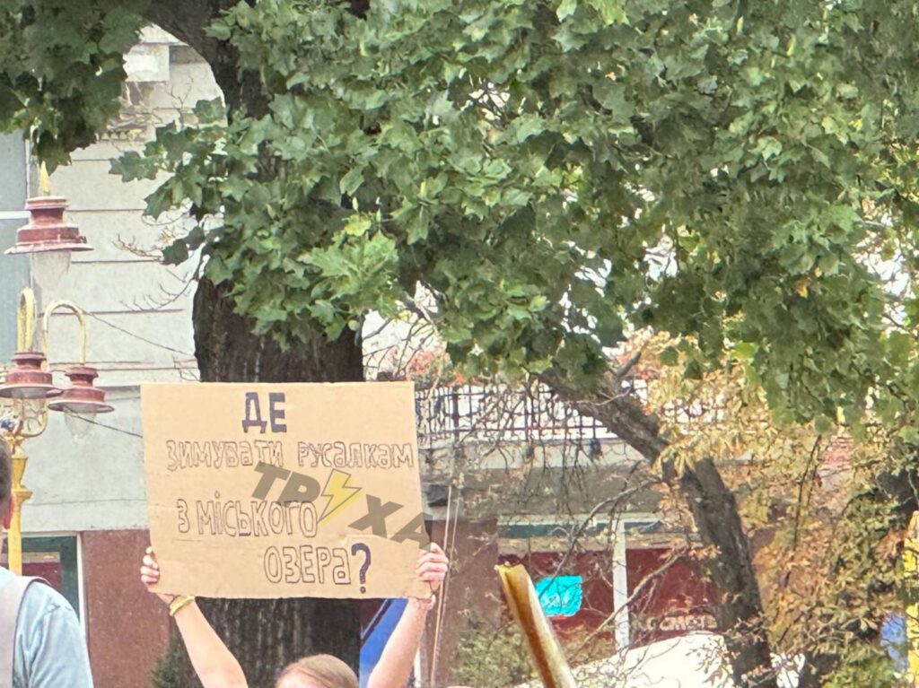 Людина тримає знак під деревом