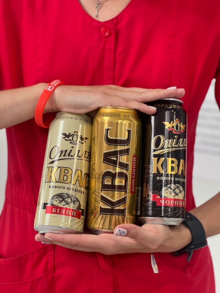 Три банки квасу Опілля у руках людини.