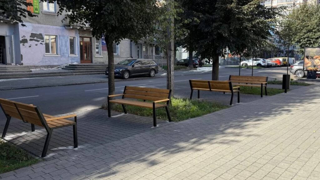 Лавки та дерева на тротуарі міської вулиці.