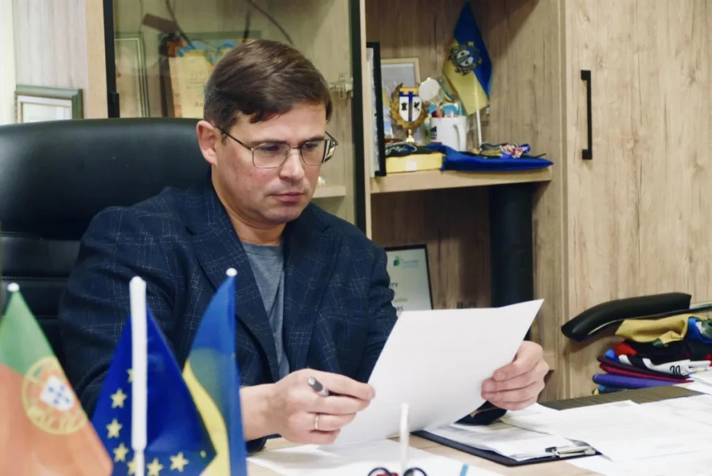 Чоловік працює за столом з документами та прапорами
