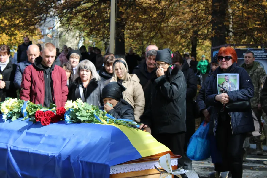 Похорон воїна з труною, вкритою українським прапором