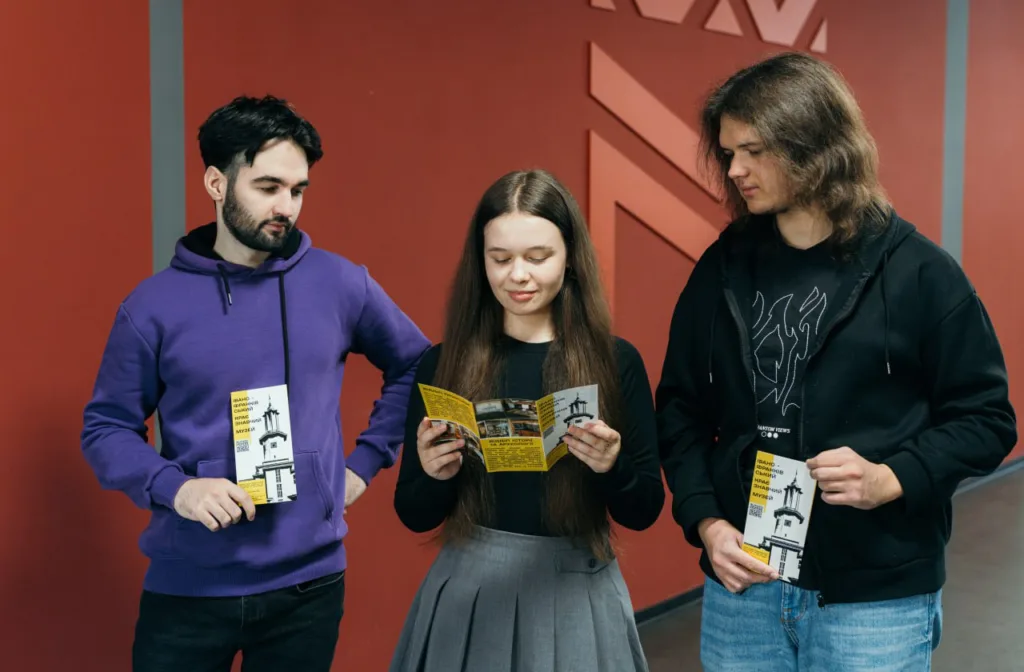 Троє студентів читають рекламні брошури у коридорі