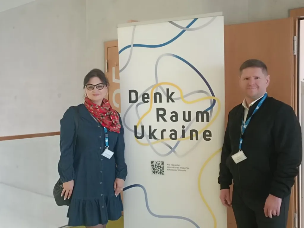Двоє людей біля банера Denk Raum Ukraine